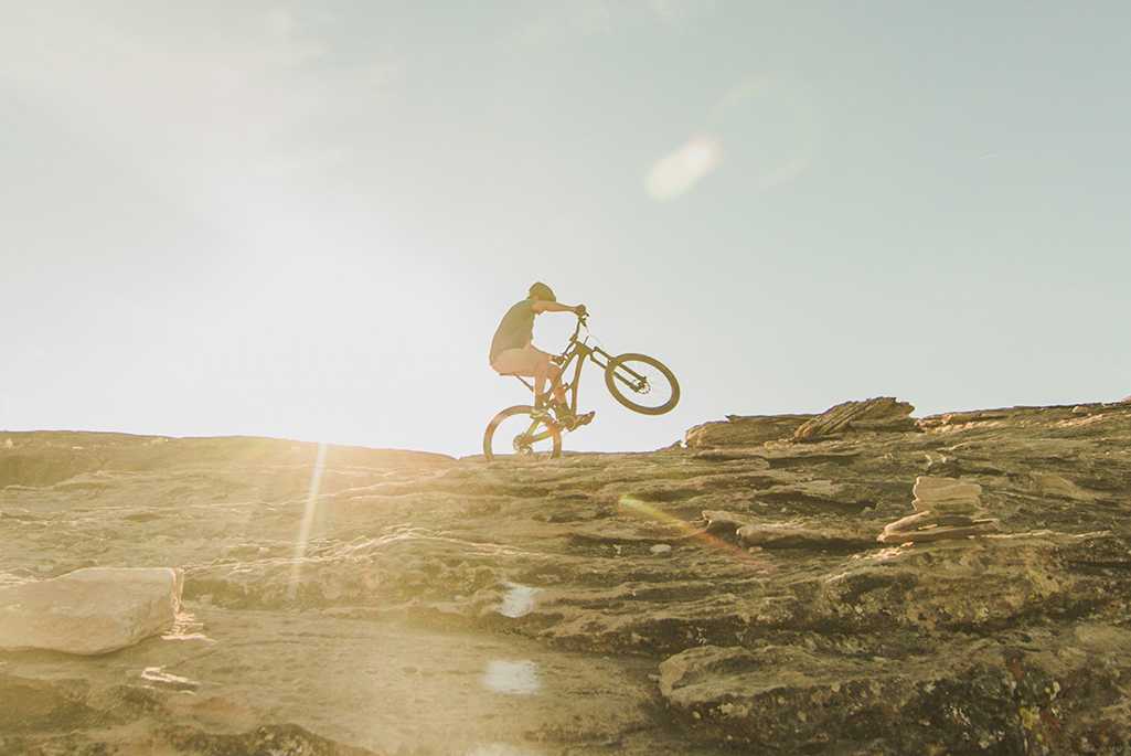 Foto på en person som cyklar på sin mountainbike på en stenklippa.